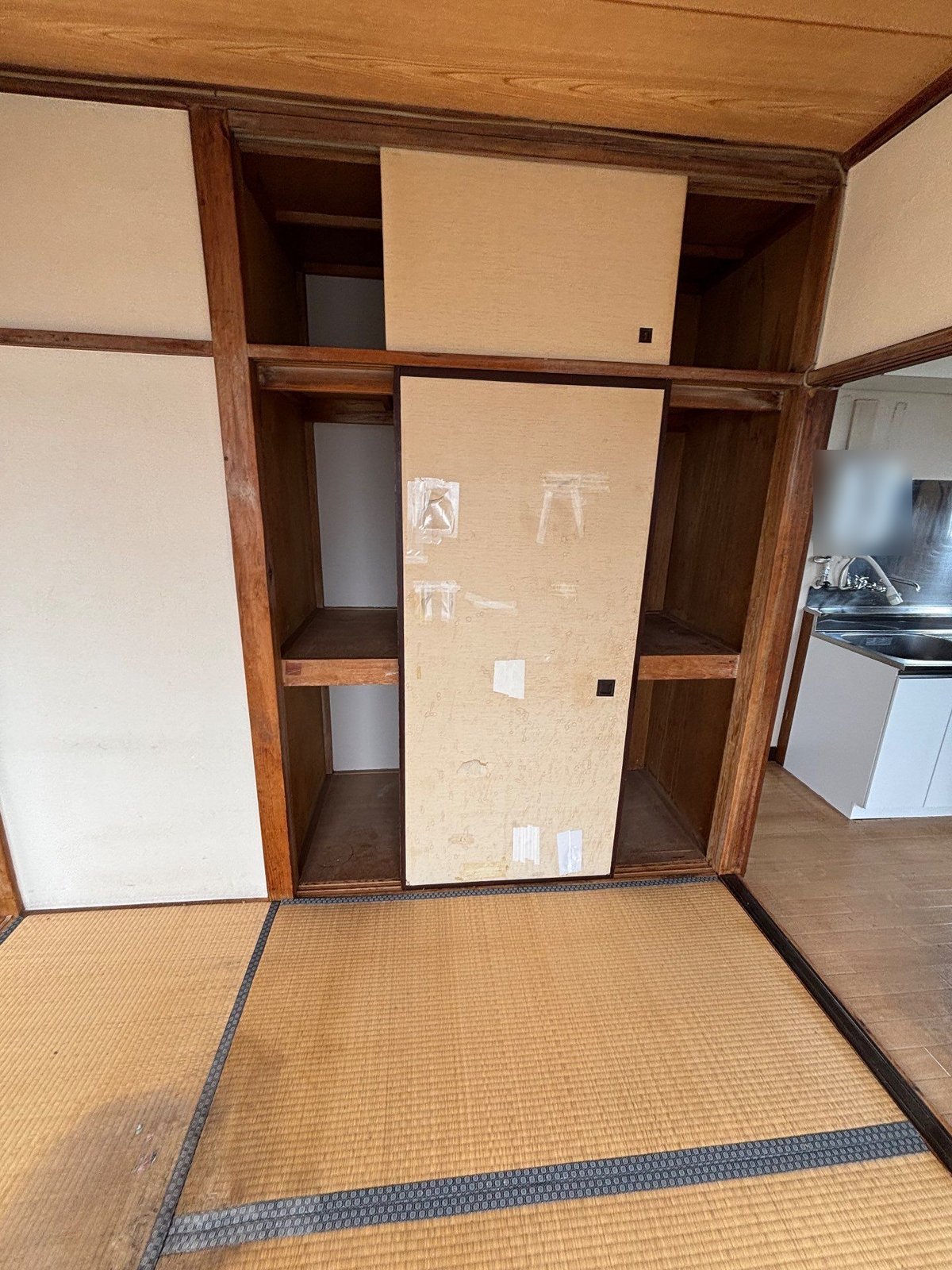和室の押入れ。ふすまの左右の上段・下段とも空になっていて、右手に台所が見える