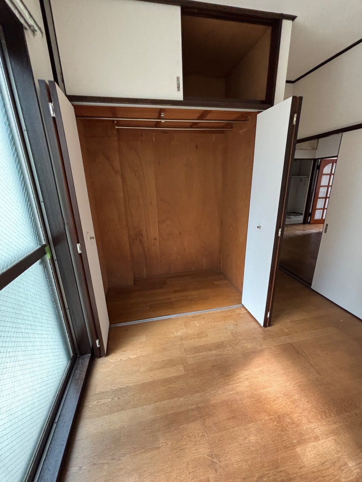 作業後の1階の洋室。クローゼットの扉と上の天袋が開いた状態で、ハンガーパイプの下も天袋の中も空になっている