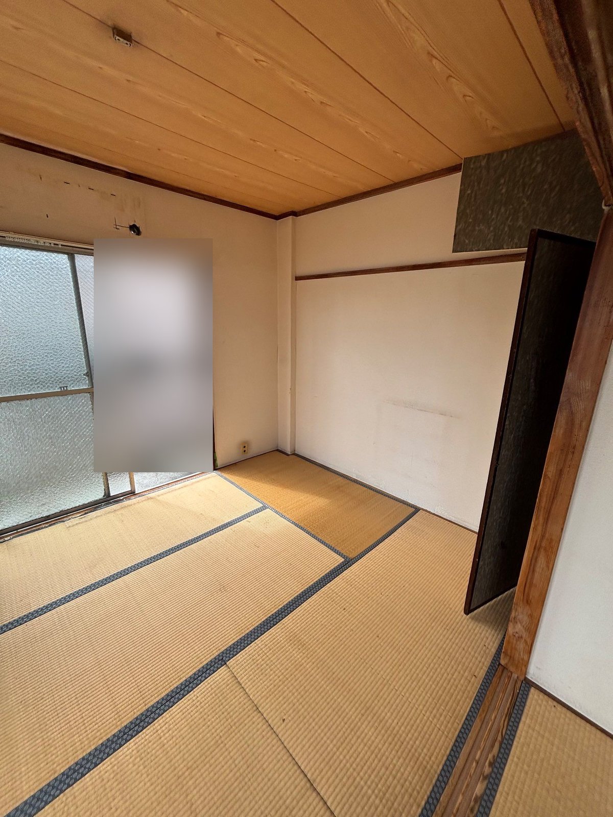 家財を運び出した後の和室。左に掃き出し窓、右に開いた押入れの戸があり、畳の上には何も残っていない
