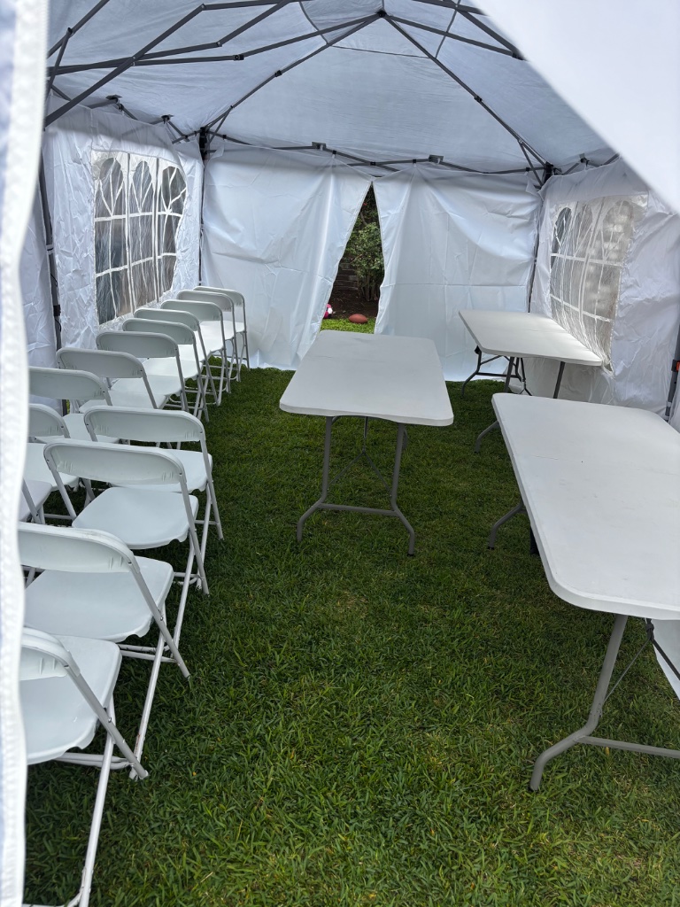 Tent interior — crisp white chairs & banquet tables 🪑