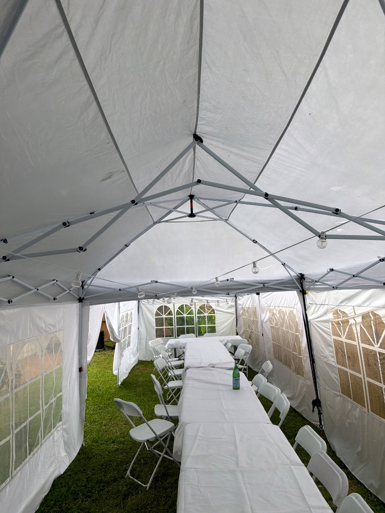 Tent interior — white linen tables & bistro lights overhead 💡