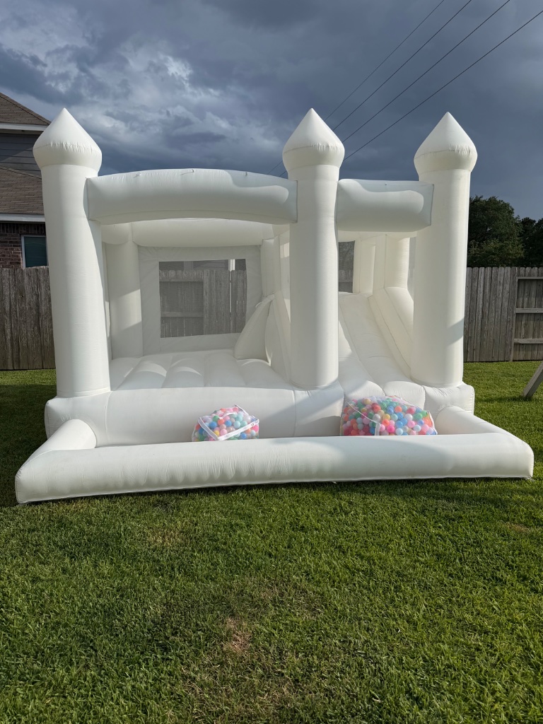 White bounce castle with ball pit on green lawn 🏰