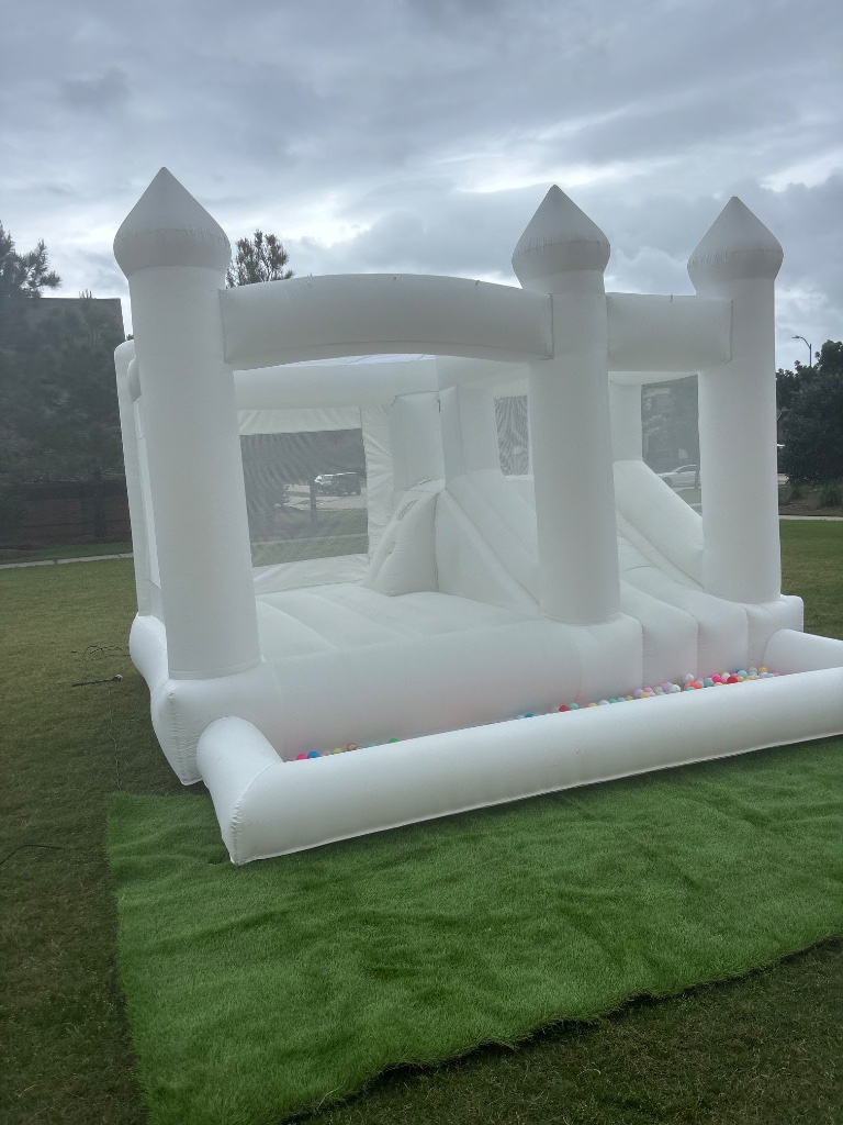 White bounce castle with ball pit on lush green turf 🏰