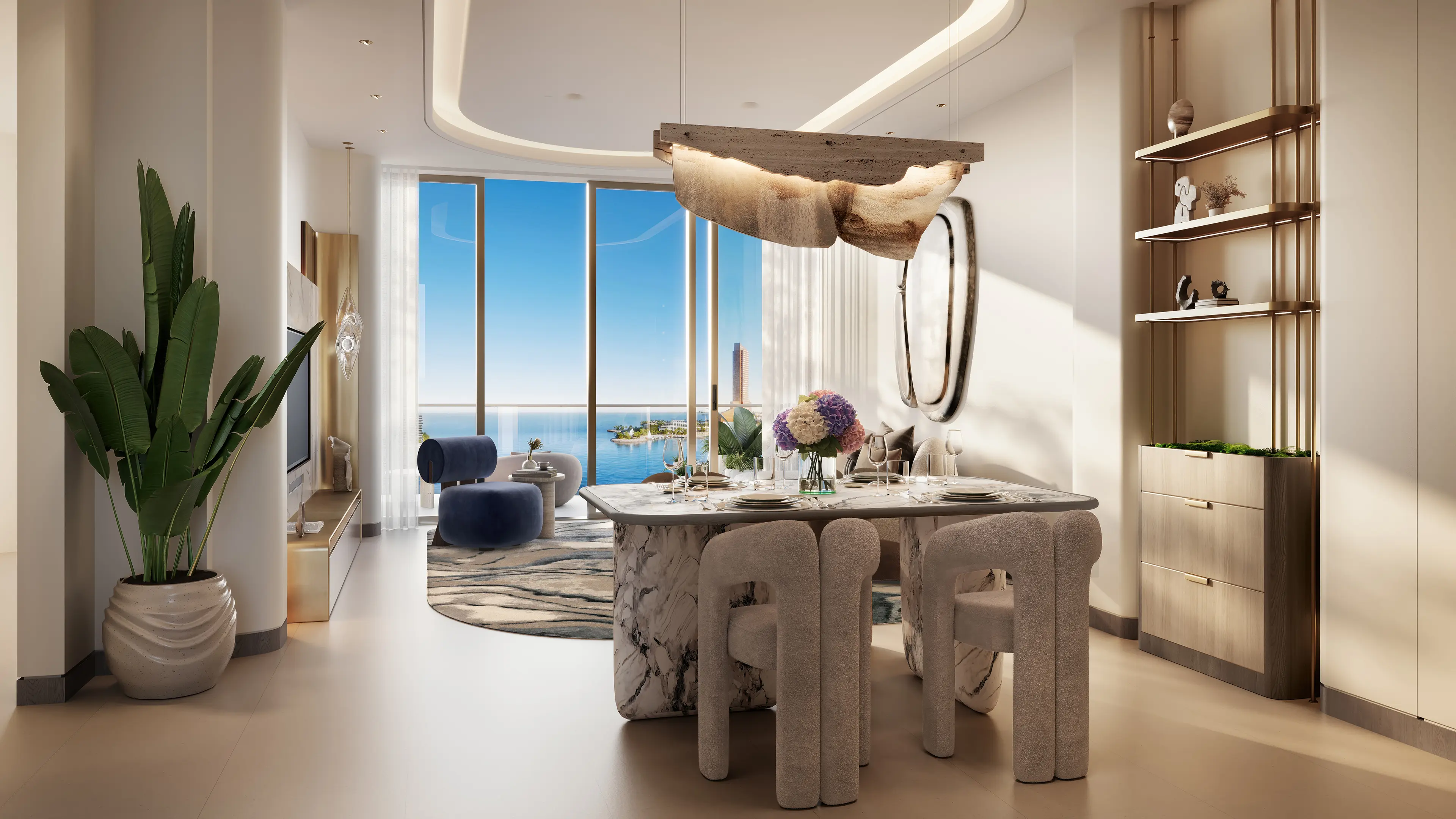 Intérieur d'appartement 1 chambre Oystra by Richmind : salon et salle à manger ouverts avec table en marbre, fauteuil bleu velours et vue panoramique sur la mer.