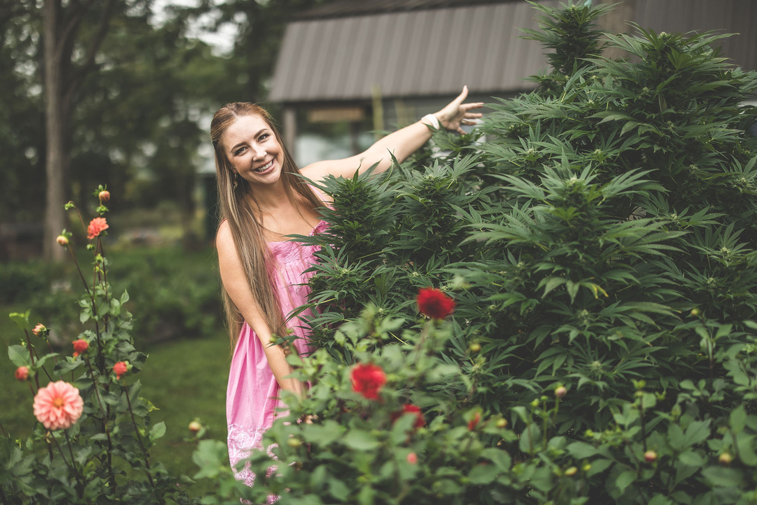 Emily smiling beside a cannabis plant in her garden