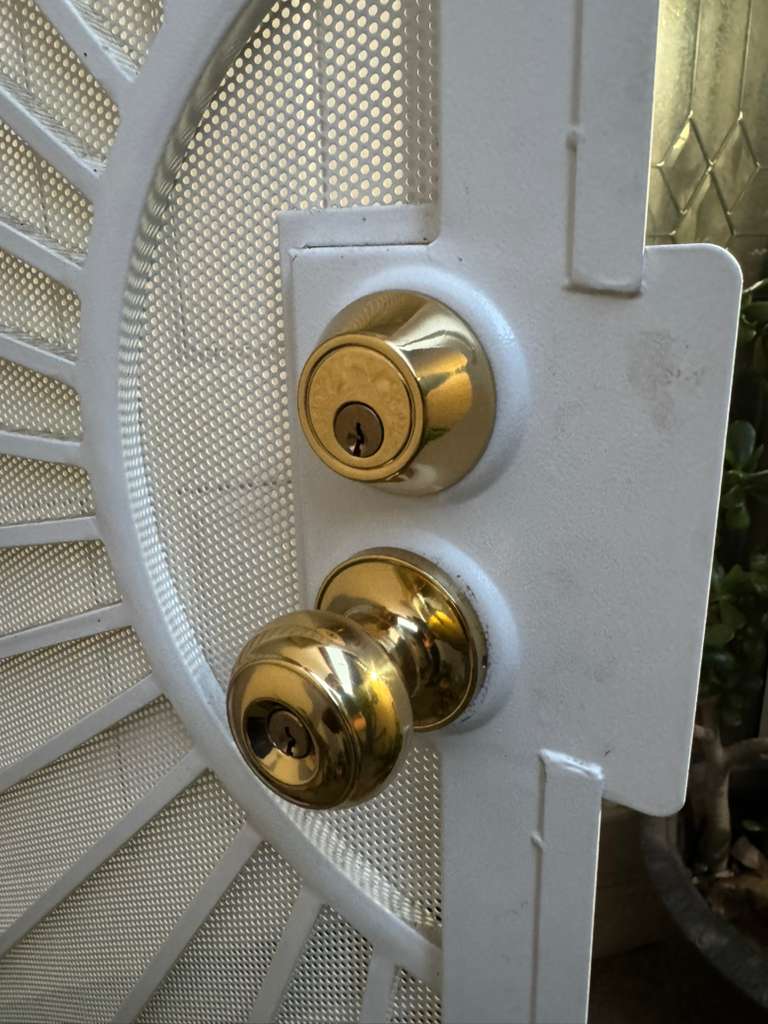 Brass lockset installed on a white security screen door