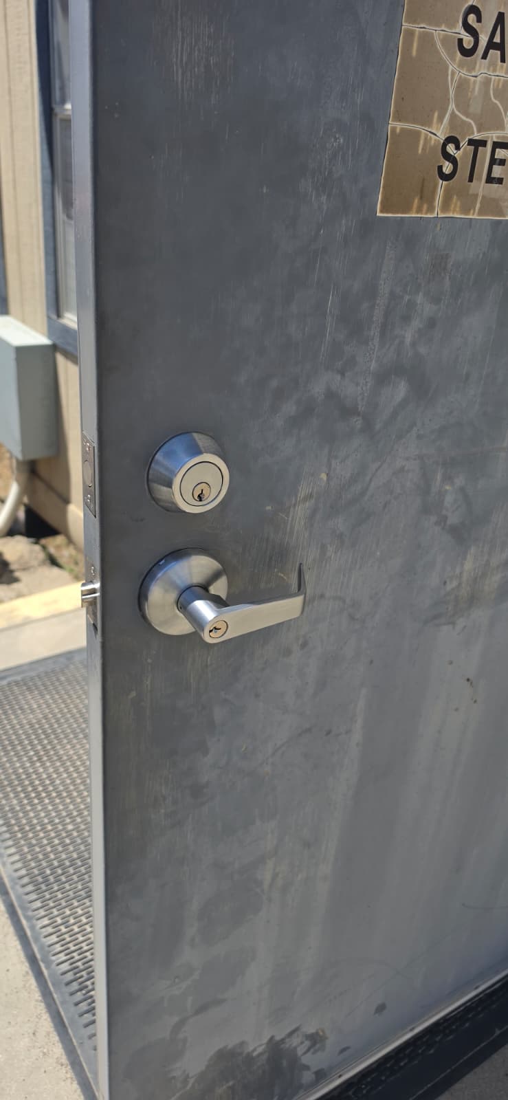 Commercial metal door with deadbolt and lever handle installed