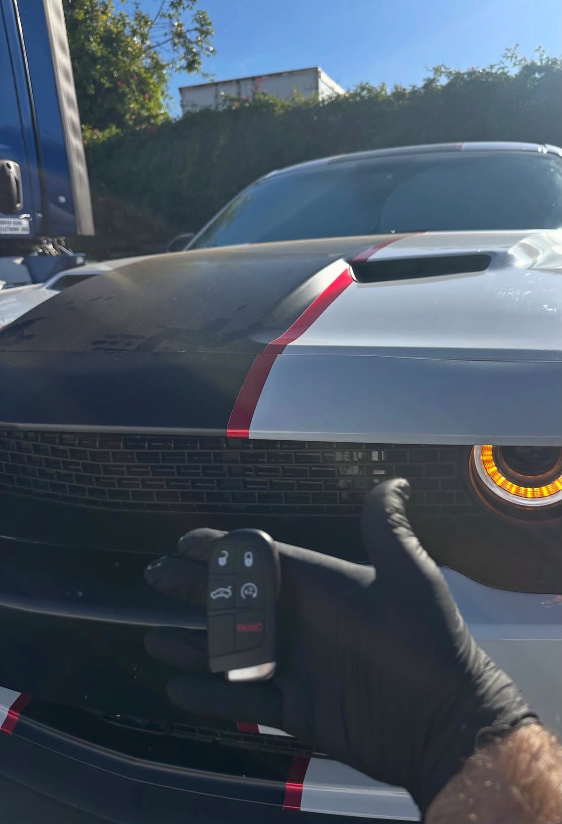 Locksmith holding a new car key fob in front of a vehicle