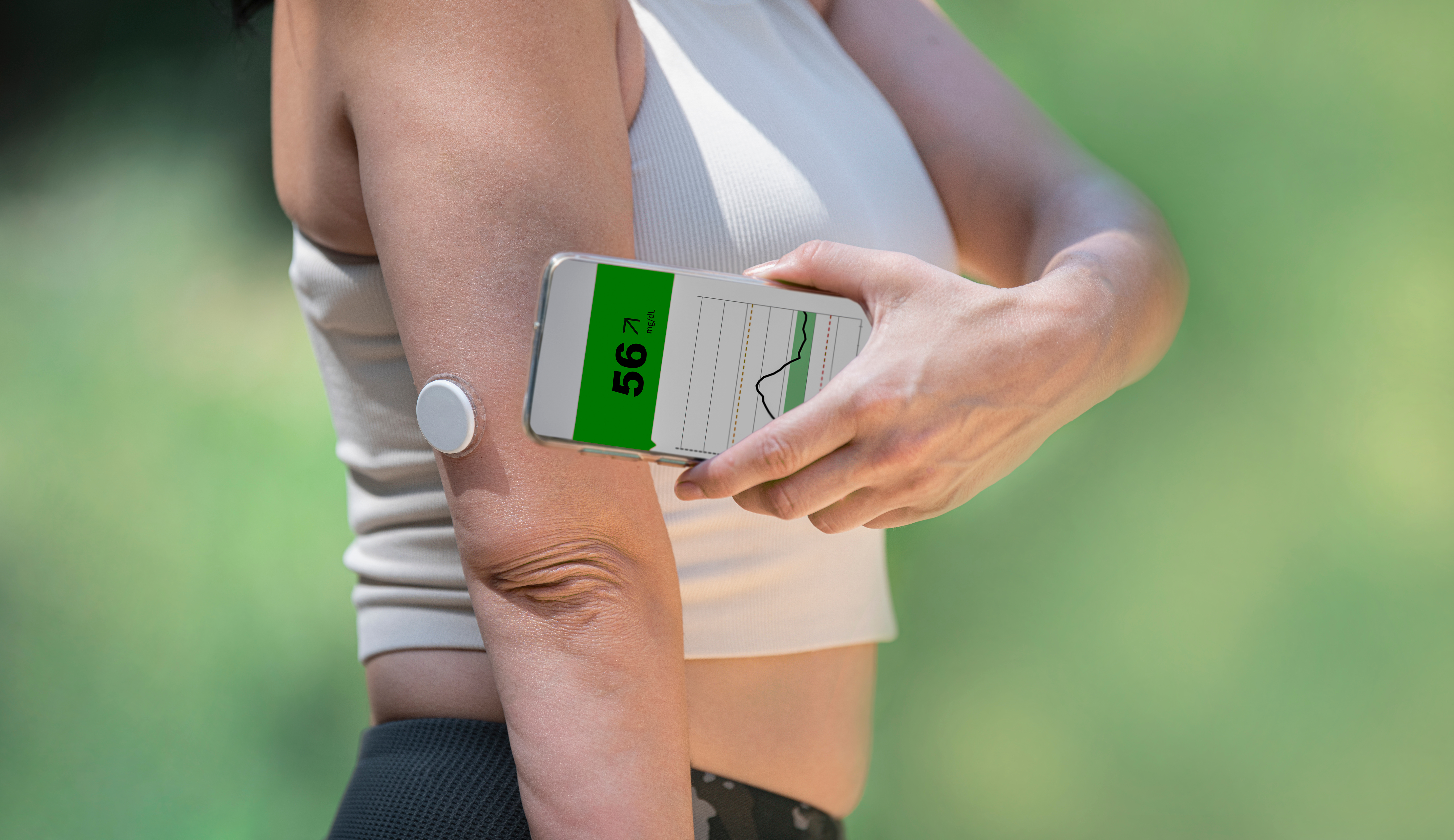 A patient checking a continuous glucose sensor with a phone app