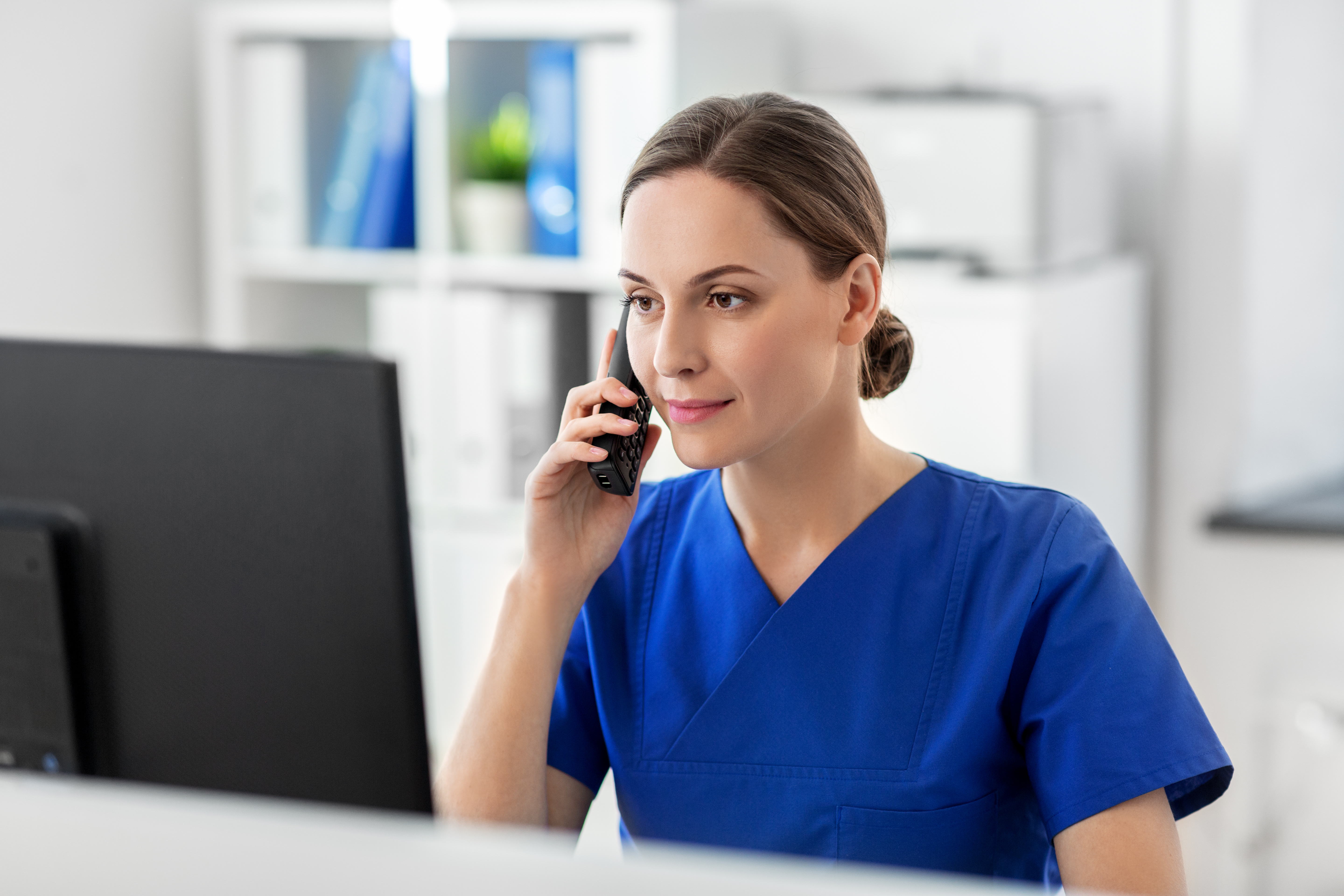 A clinician at a computer in a clinic, handling patient messages