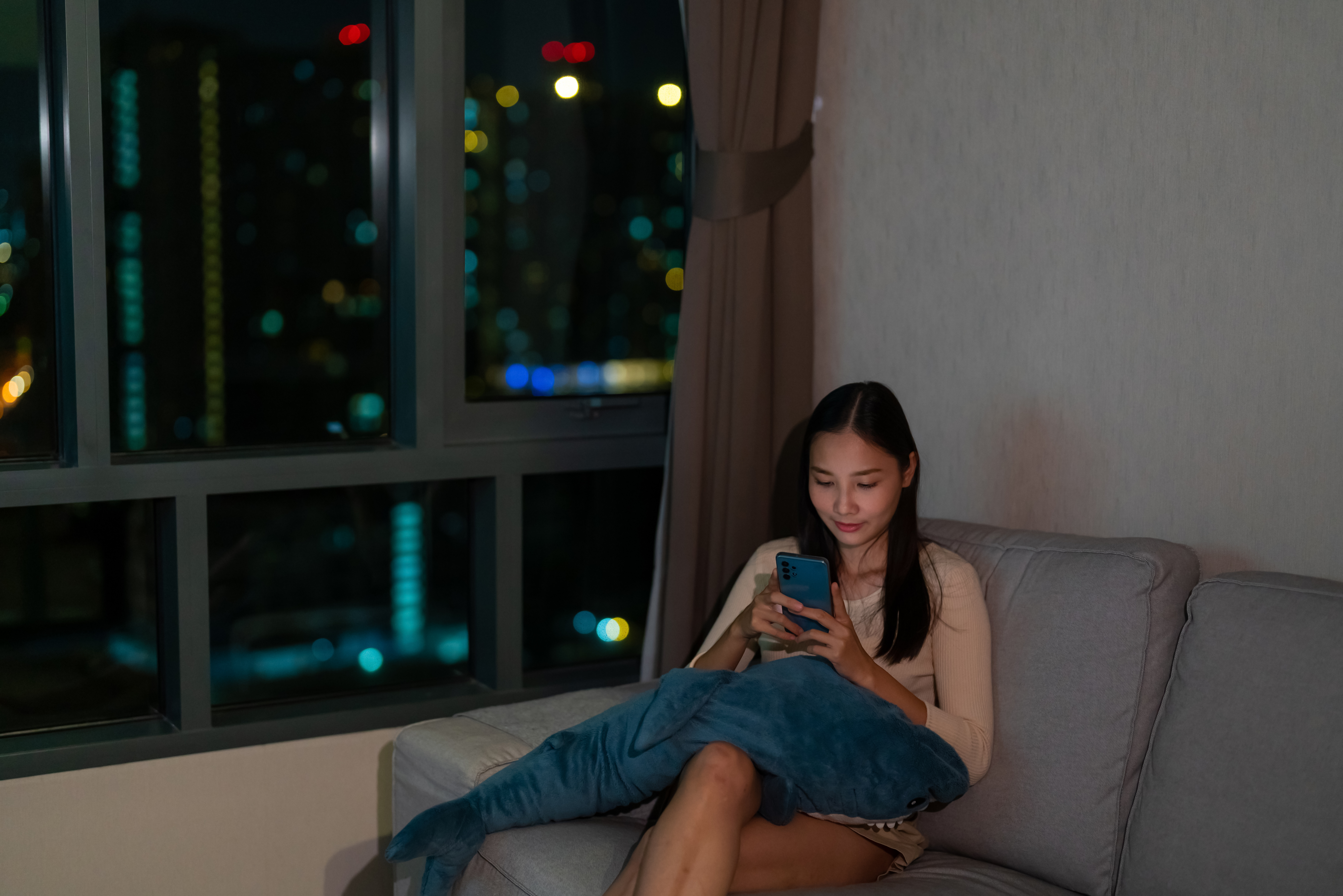 A woman at home in the evening, looking at her phone