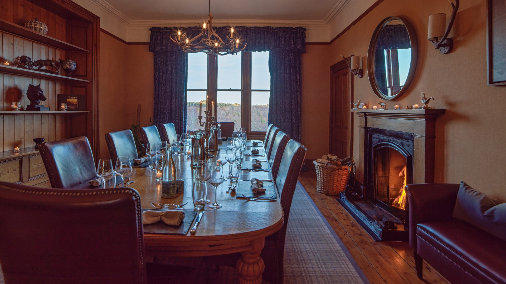The dining room at Alladale Lodge with a long table and open fire