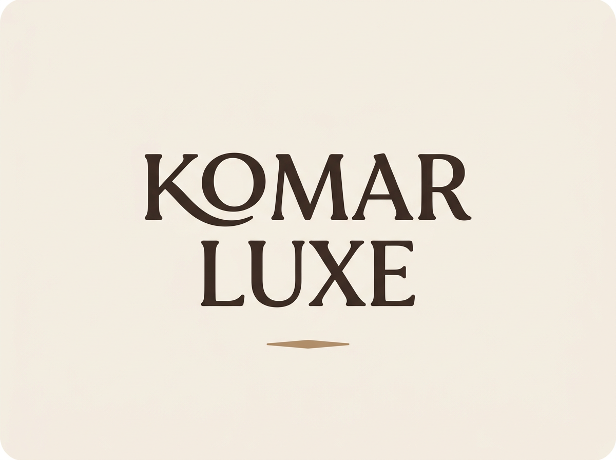 Komar Luxe Storied Signature logo in espresso serif lettering on warm parchment