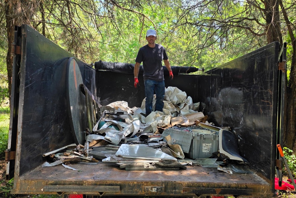 Cleanout Brothers team member standing in truck bed full of junk for Nashville junk removal and cleanout services