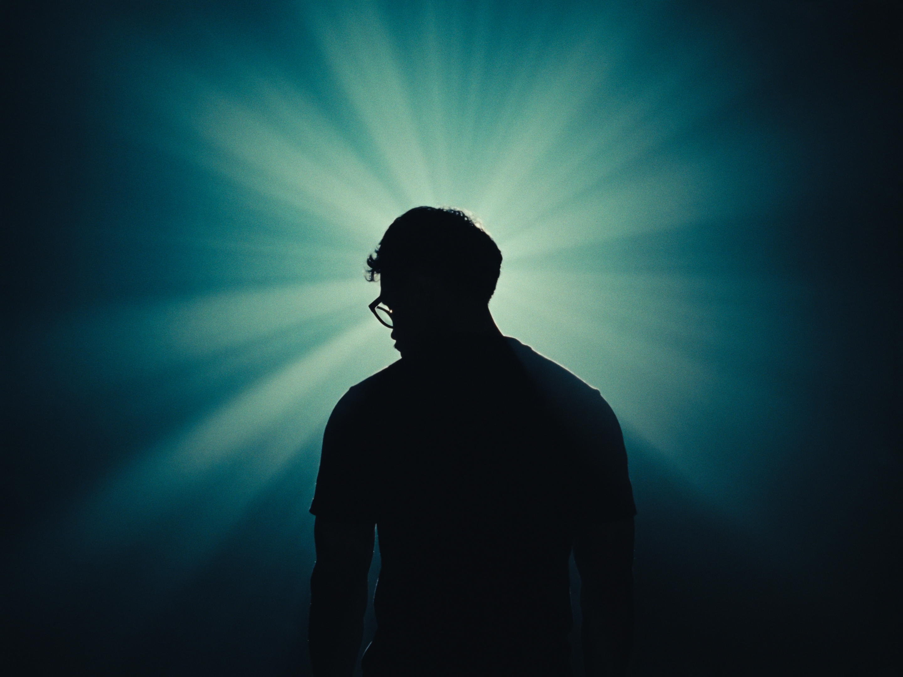 Silhouette against a teal starburst light