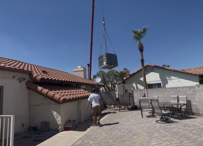 Crane lowering a full-sized central HVAC unit into place at a Phoenix home