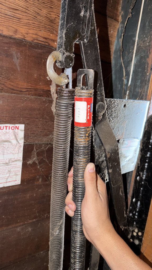 Garage door cable replacement Los Angeles Worn garage door cable and spring assembly held by an MSB technician before cable replacement in Los Angeles