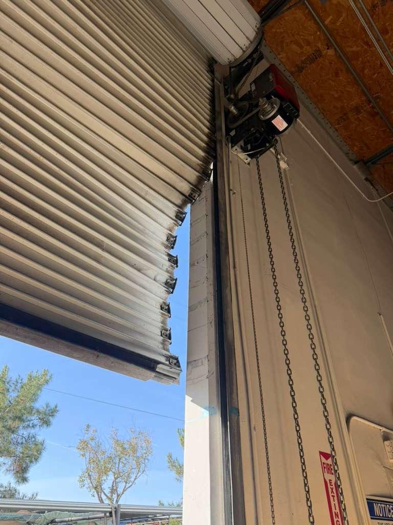 Commercial roll-up garage door with chain-drive operator being serviced at a Los Angeles business