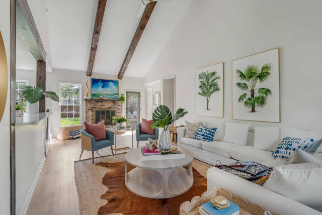 Living room with vaulted beams, teal armchairs, and layered rugs