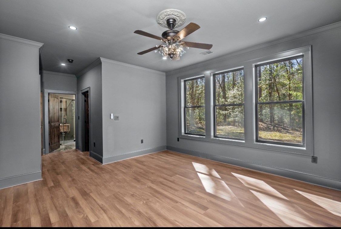 Grey bedroom with triple windows overlooking the woods