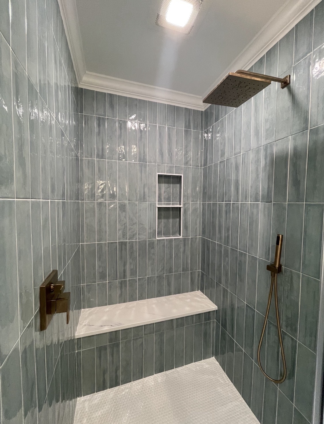 Walk-in shower with rainfall showerhead and tiled bench