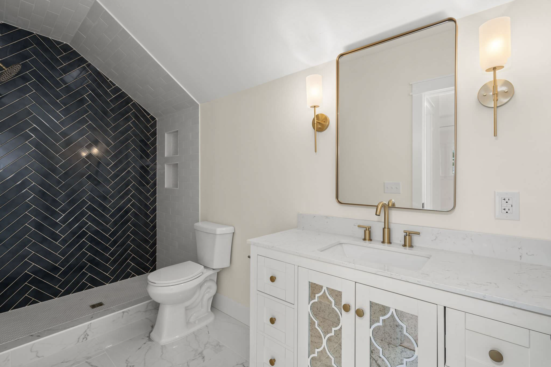 Bath with mirrored vanity doors and herringbone shower tile