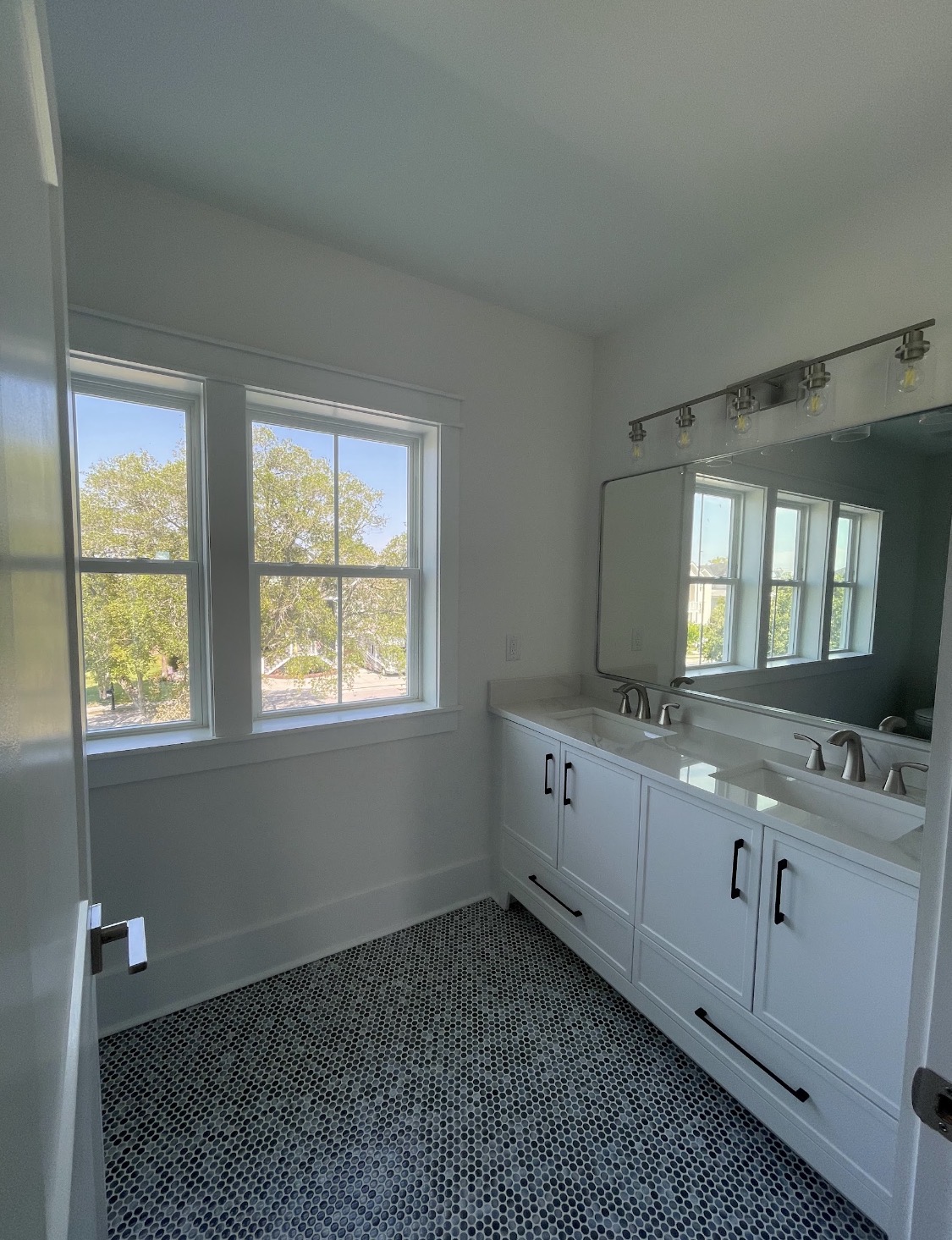 White dual-sink vanity with penny-tile floor