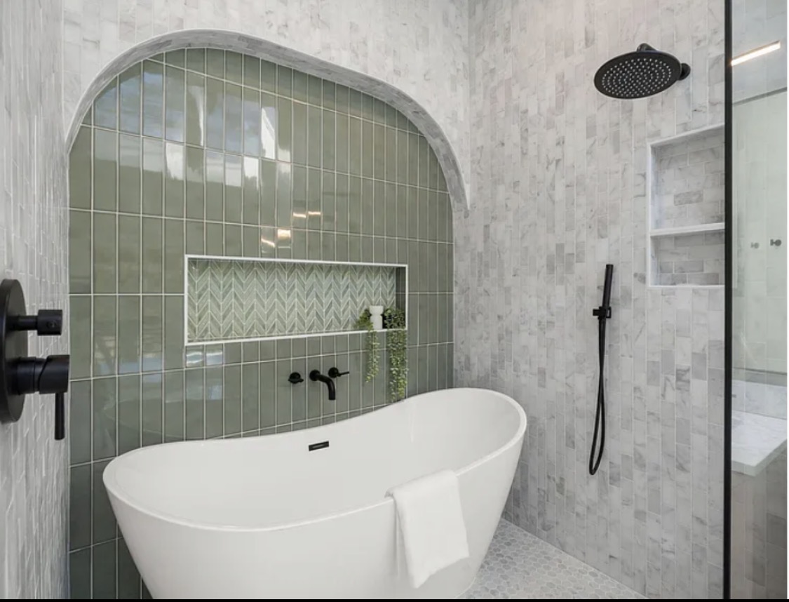 Freestanding soaking tub in sage-green arched alcove