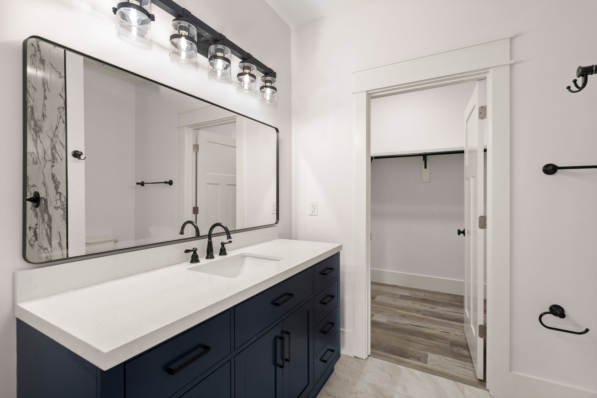 Navy vanity with five-light fixture and closet doorway