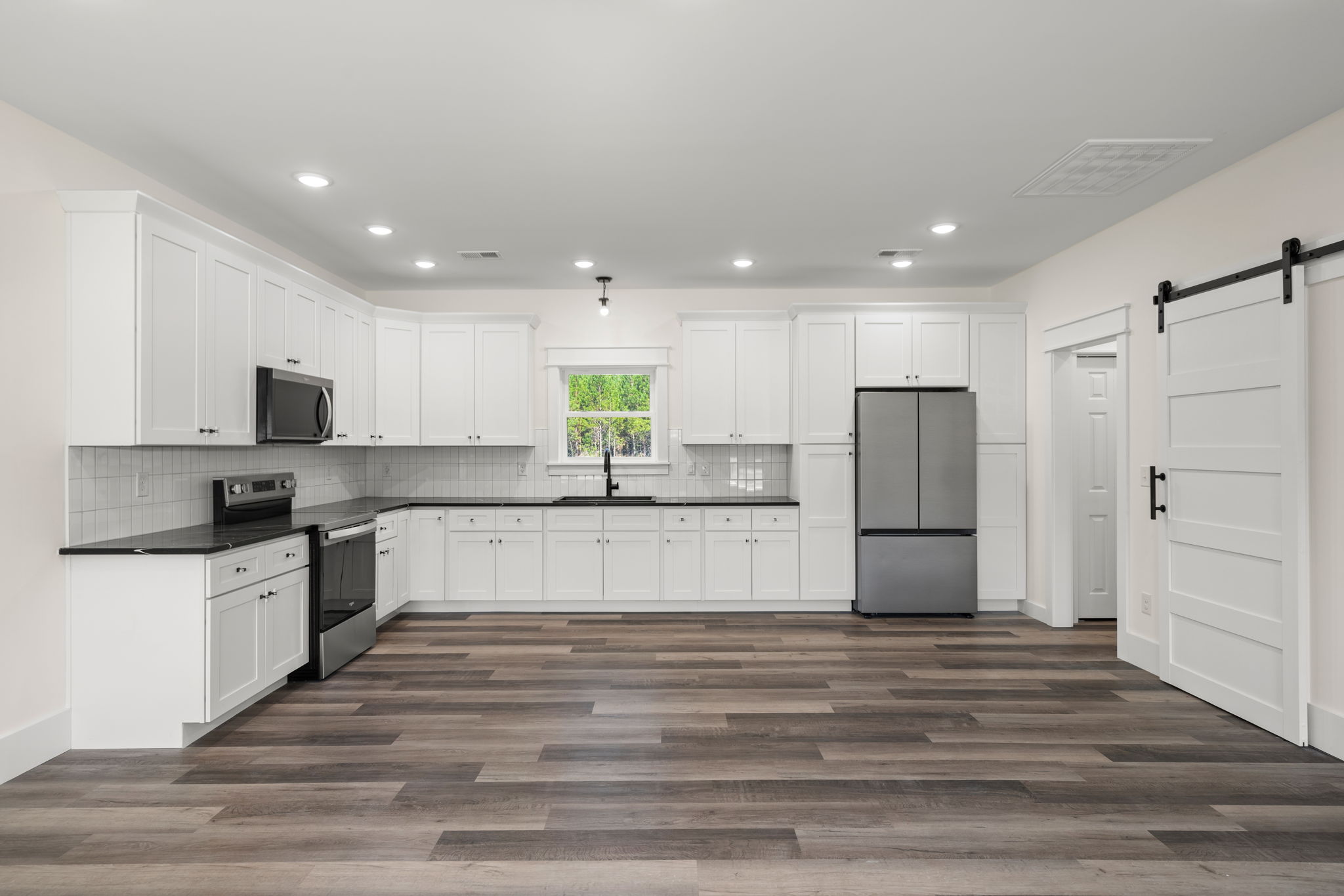 Kitchen with white shaker cabinets, subway tile, and black hardware