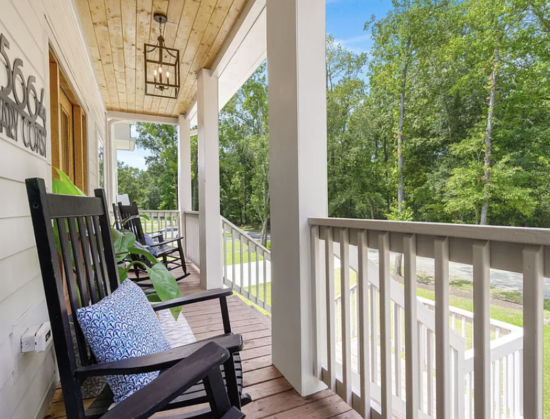 Covered front porch with rocking chairs and wood ceiling