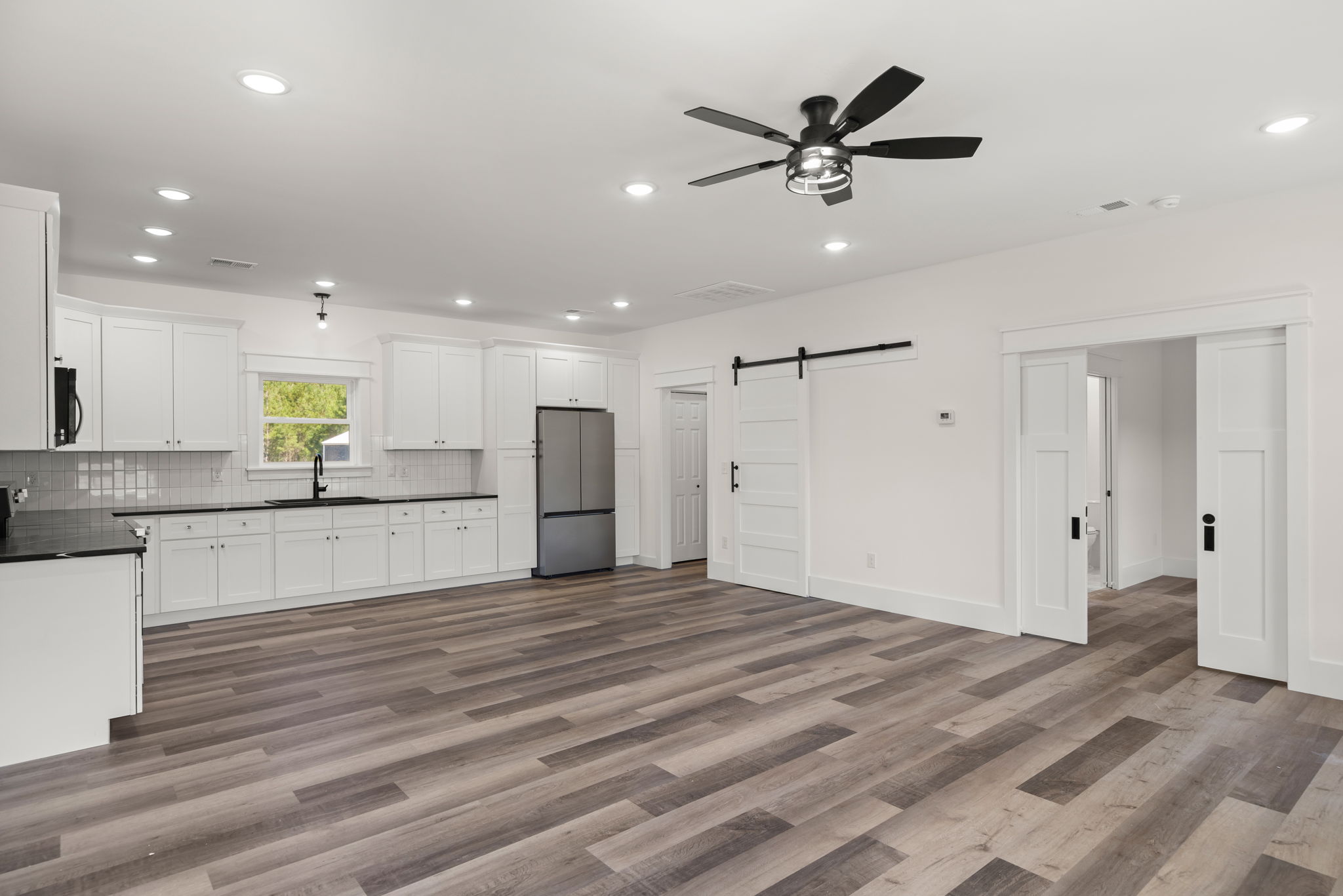 Open kitchen with black quartz island and double sliding barn door
