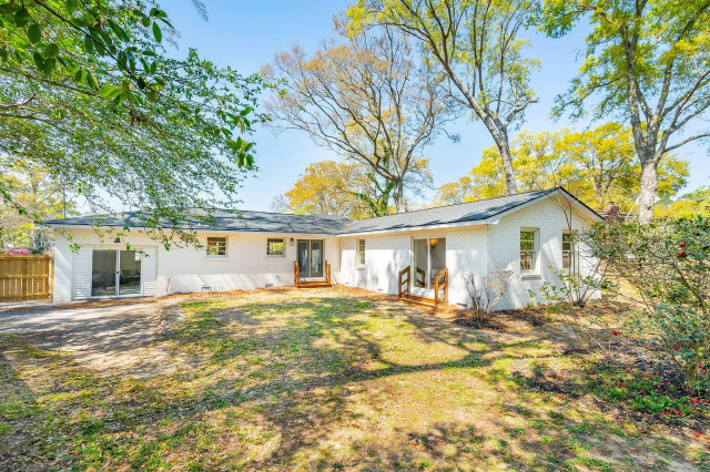 Rear exterior with sliding glass doors and wooded yard
