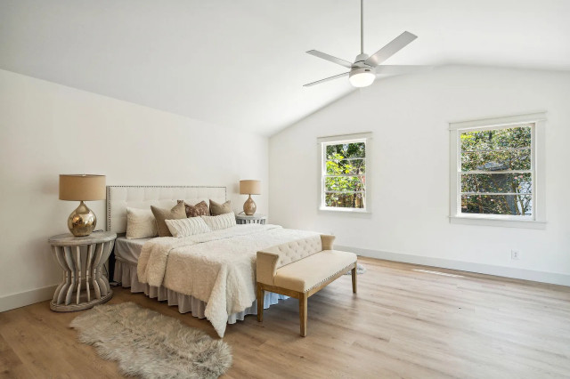 Vaulted primary bedroom with tufted headboard