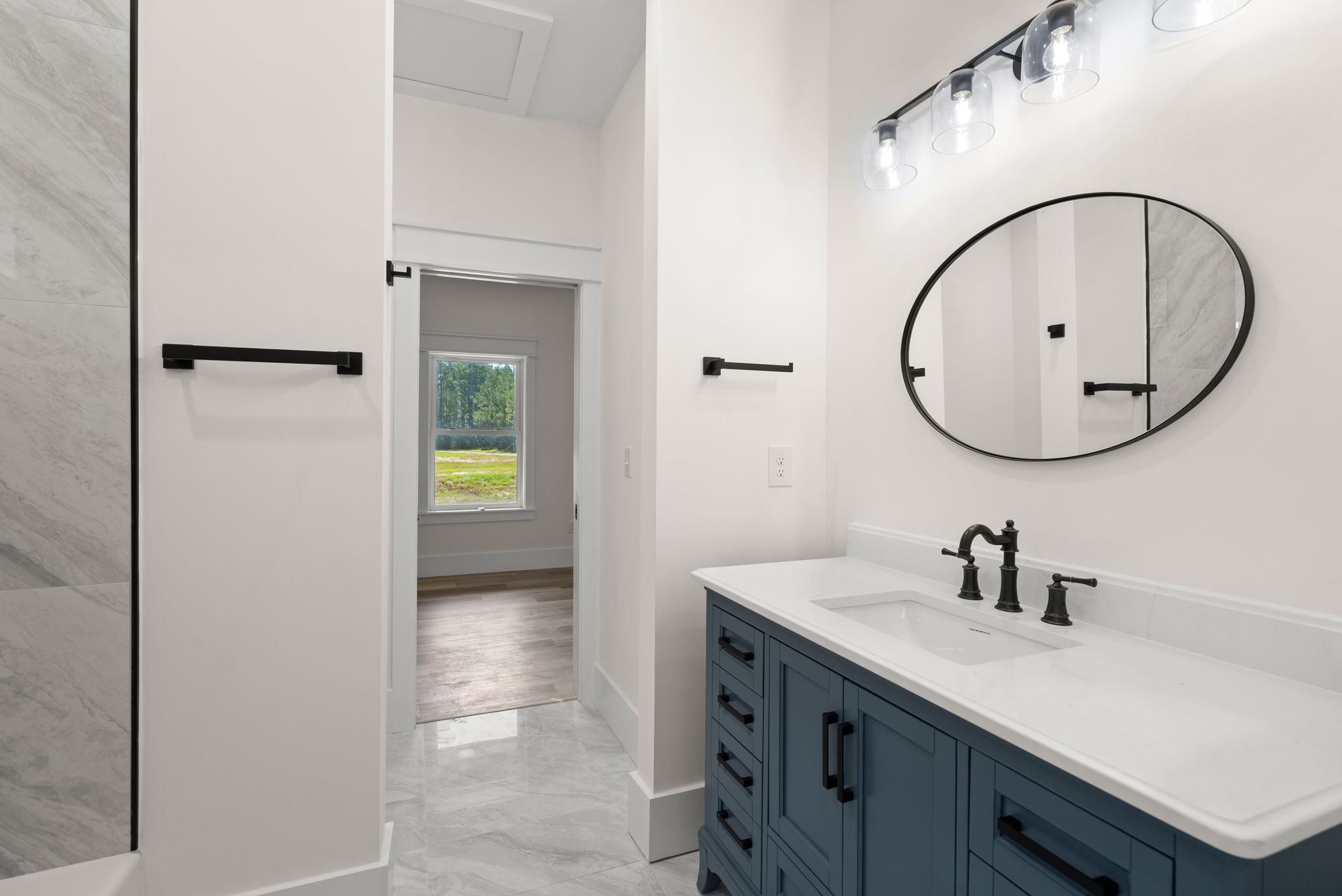 Navy vanity bathroom with oval black-framed mirror