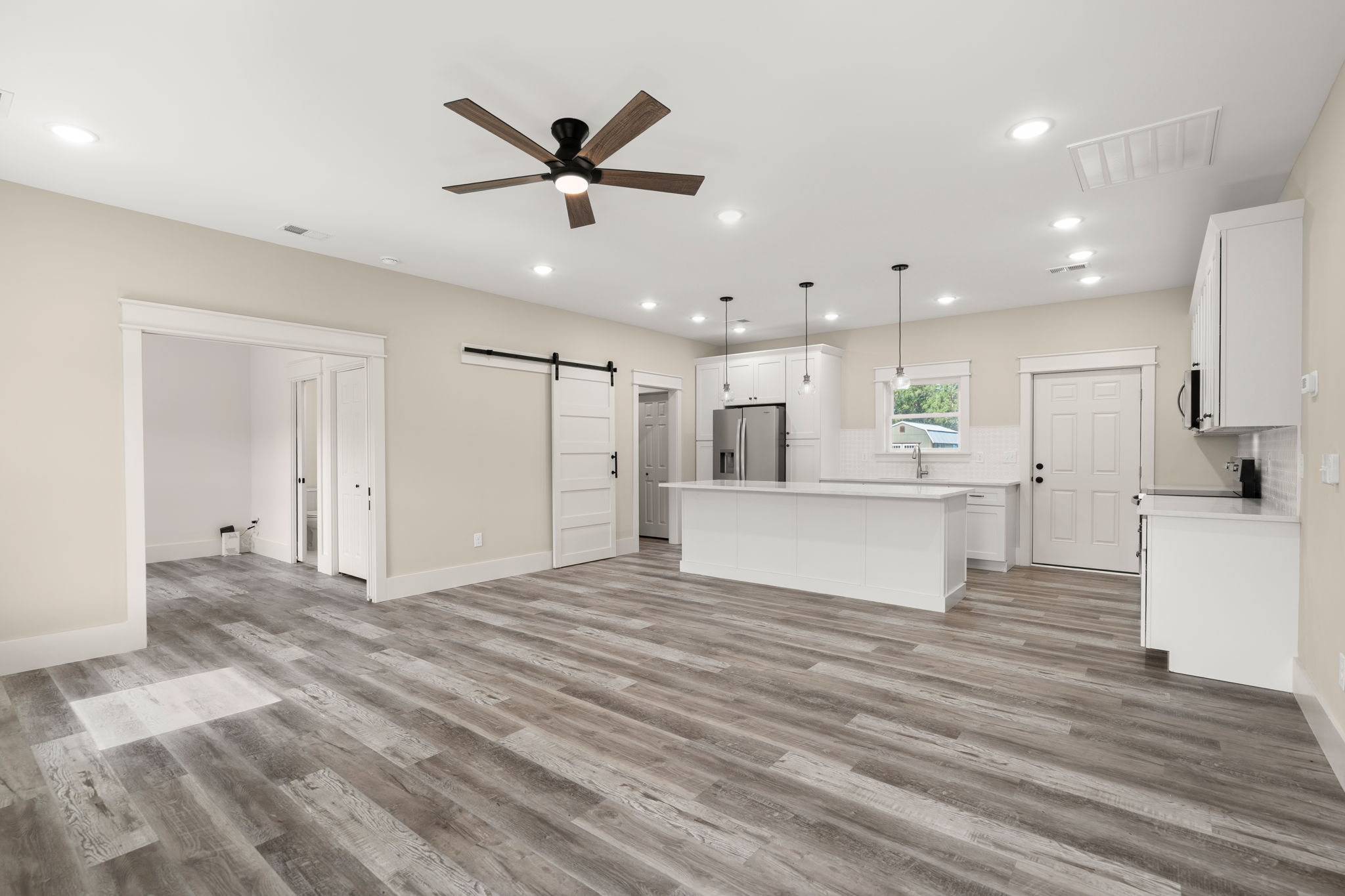 Open kitchen and living area with white island and barn door