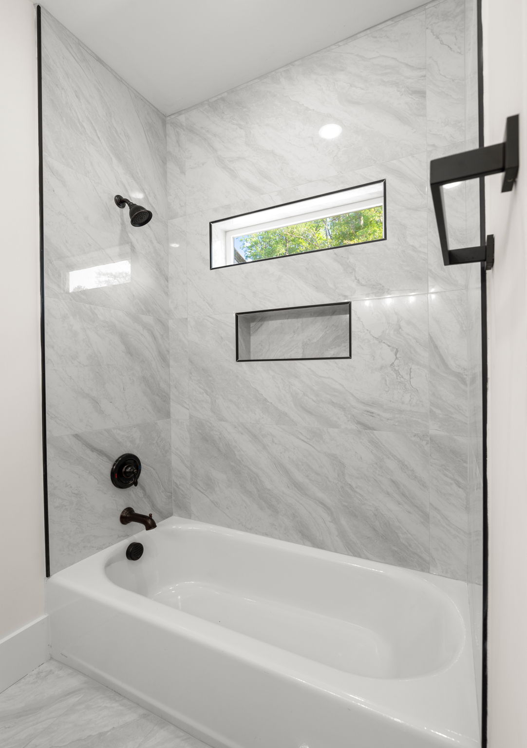Tub-shower combo with marble tile surround and black fixtures