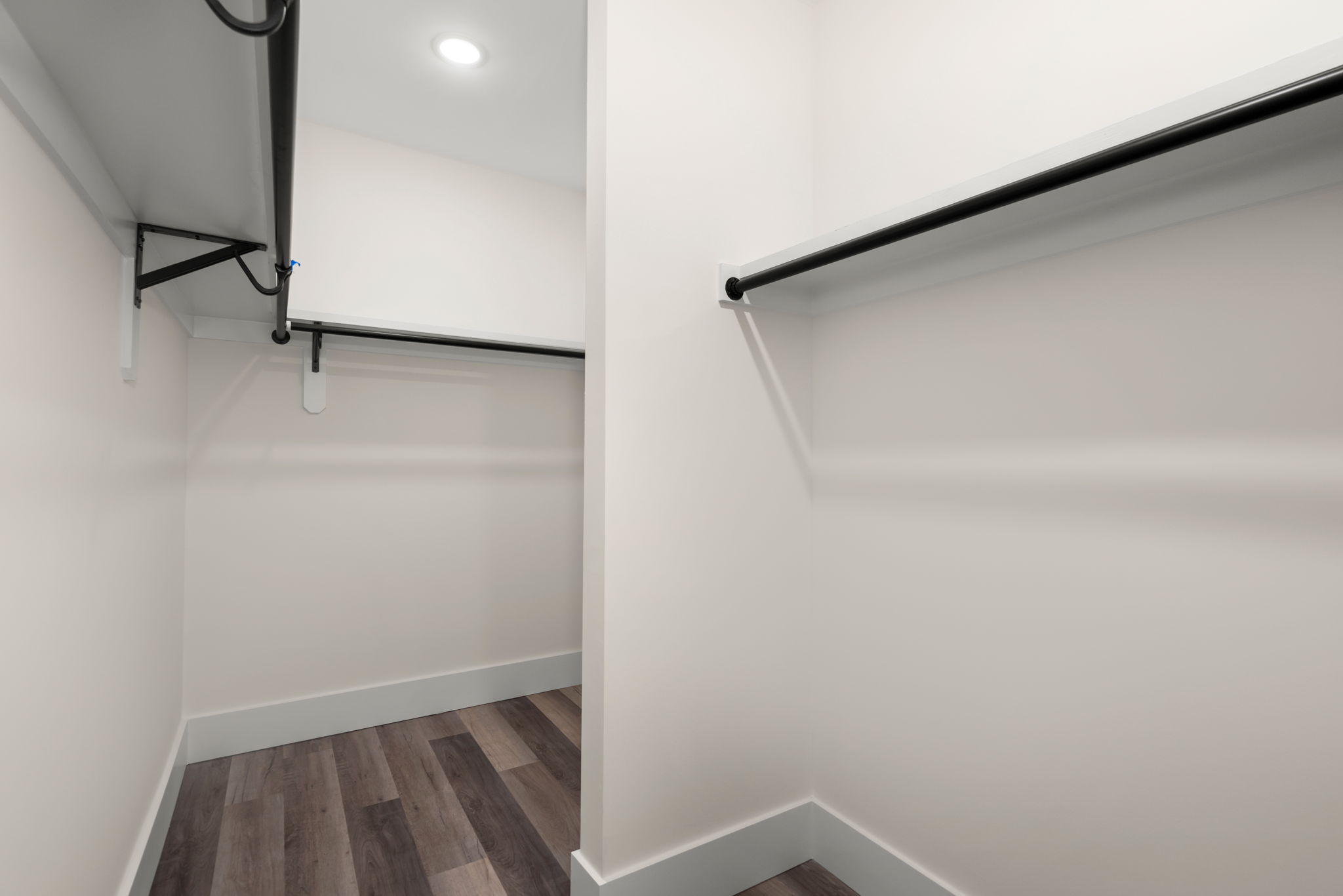 Walk-in closet with black hanging rods and white shelving