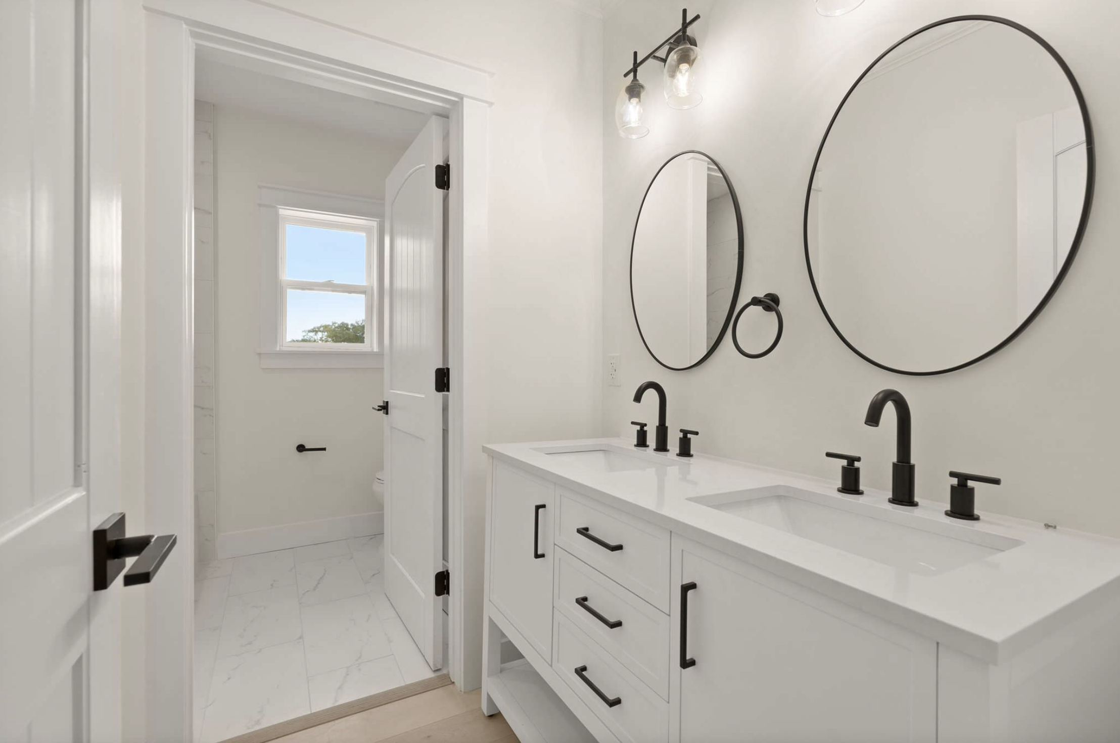 Double vanity bath with black fixtures and water closet
