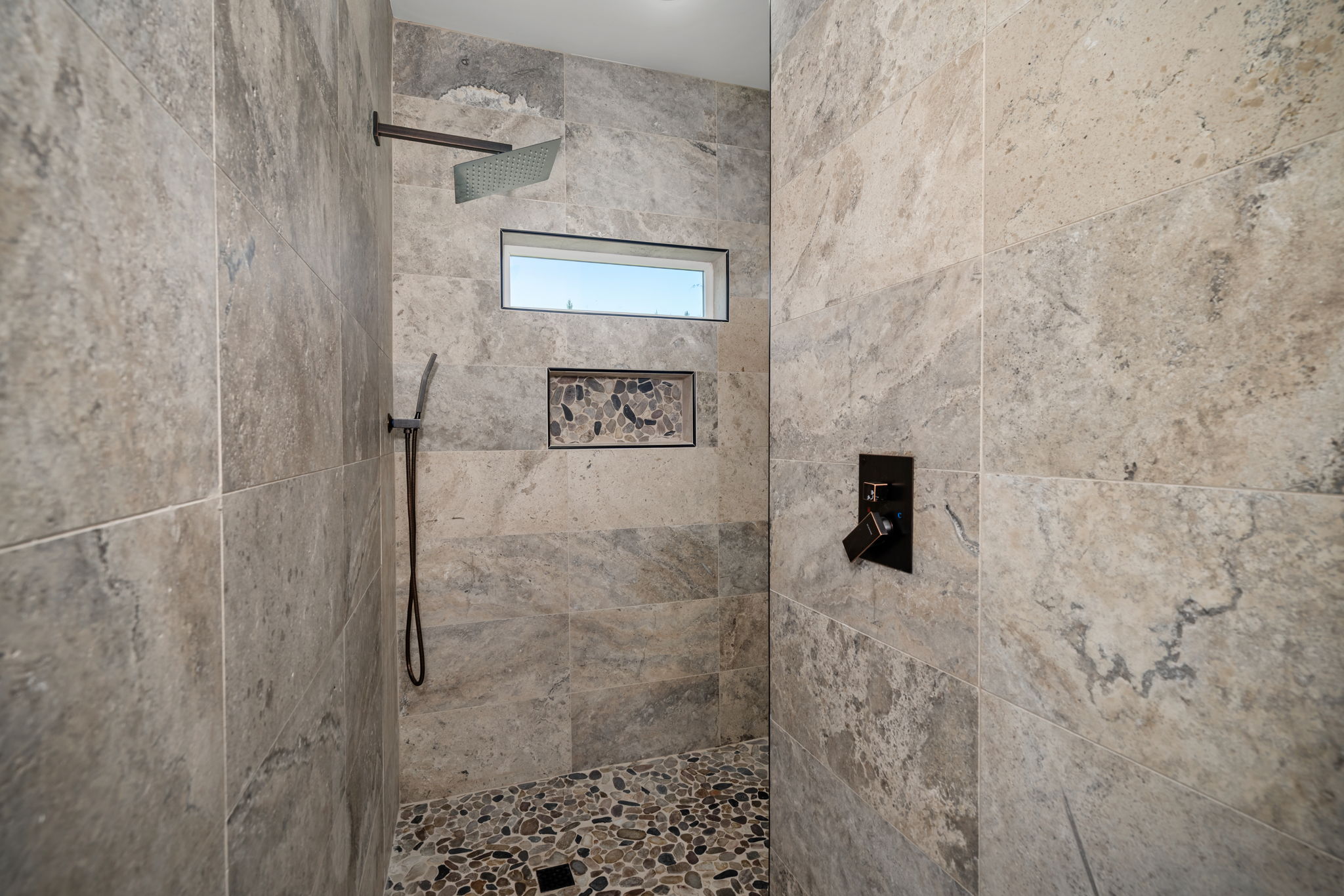 Walk-in shower with river-stone floor, slate tile, and rainfall head