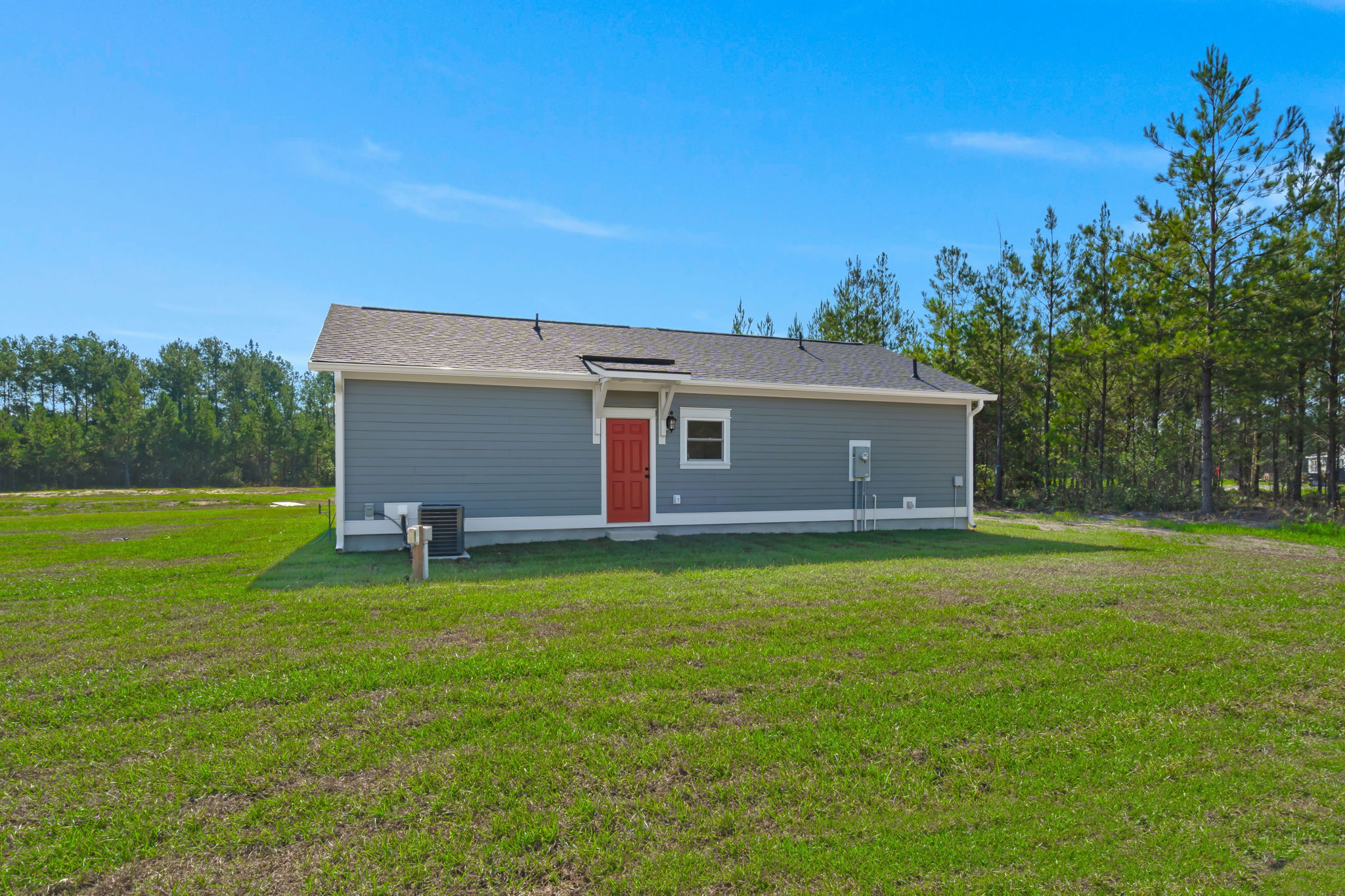 Side elevation of the gray farmhouse with red entry door