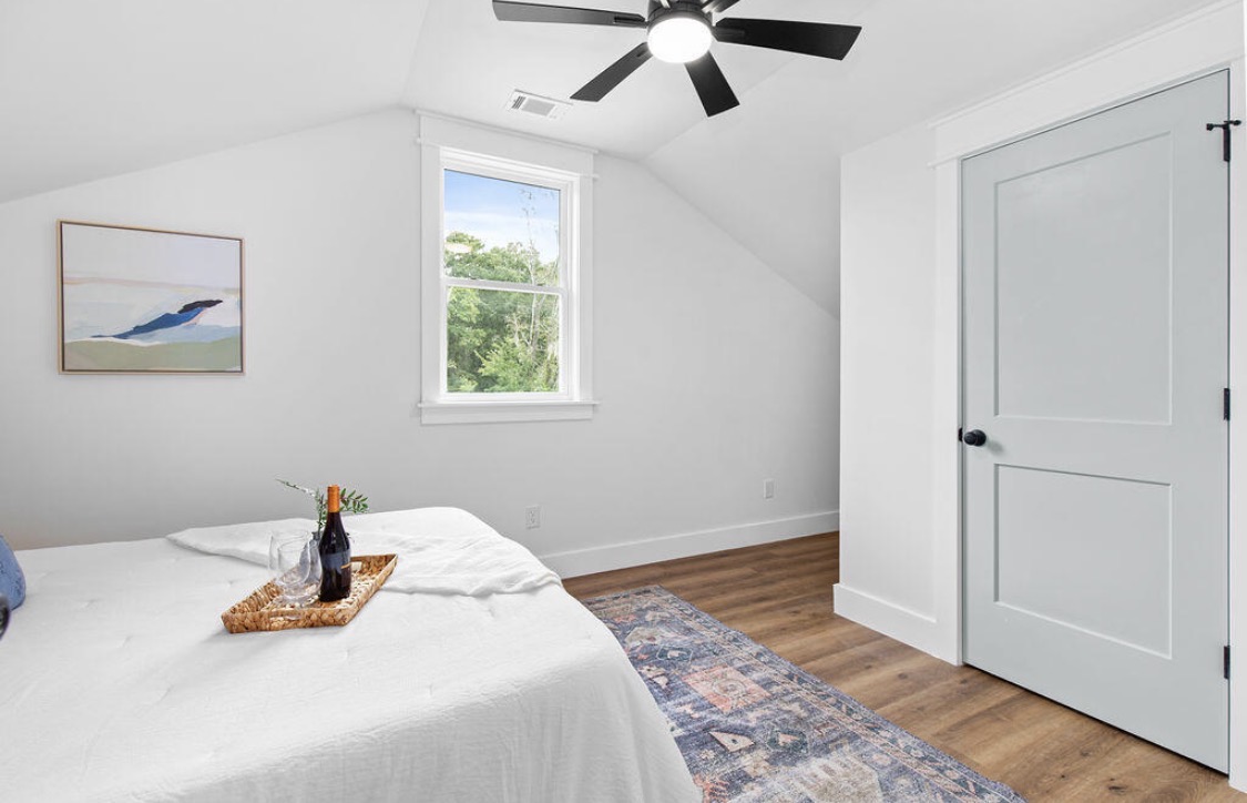 Bedroom with angled ceiling and coastal landscape art
