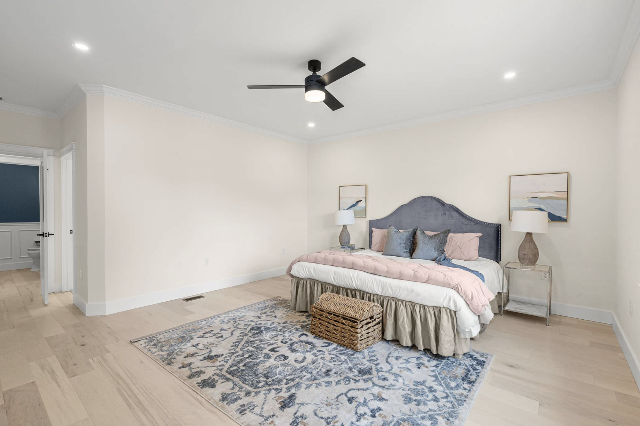 Primary bedroom with upholstered headboard and wicker trunk