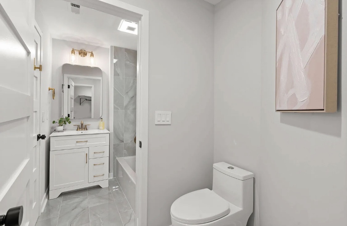 Ensuite bathroom with white shaker vanity and brass lighting
