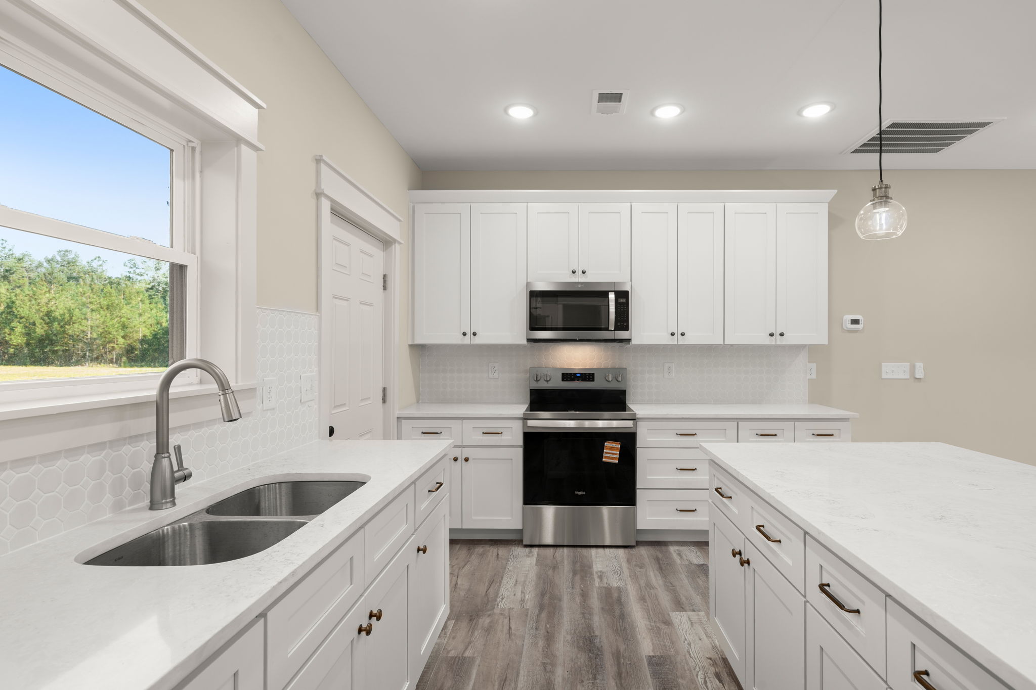 White island kitchen with hexagon tile backsplash and stainless appliances