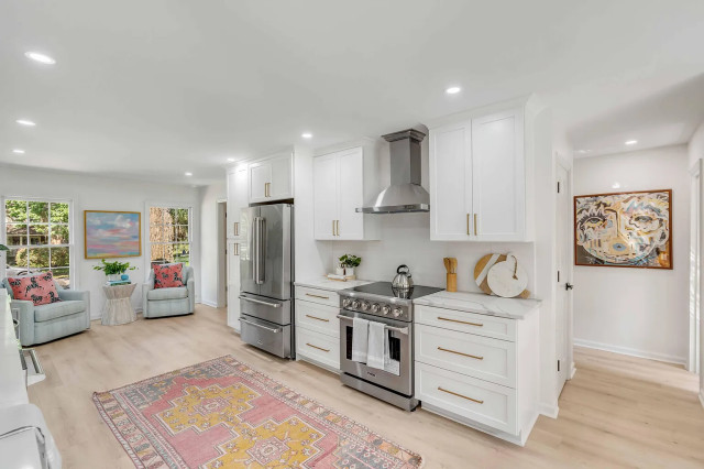 White shaker kitchen with stainless range and blue accent chairs