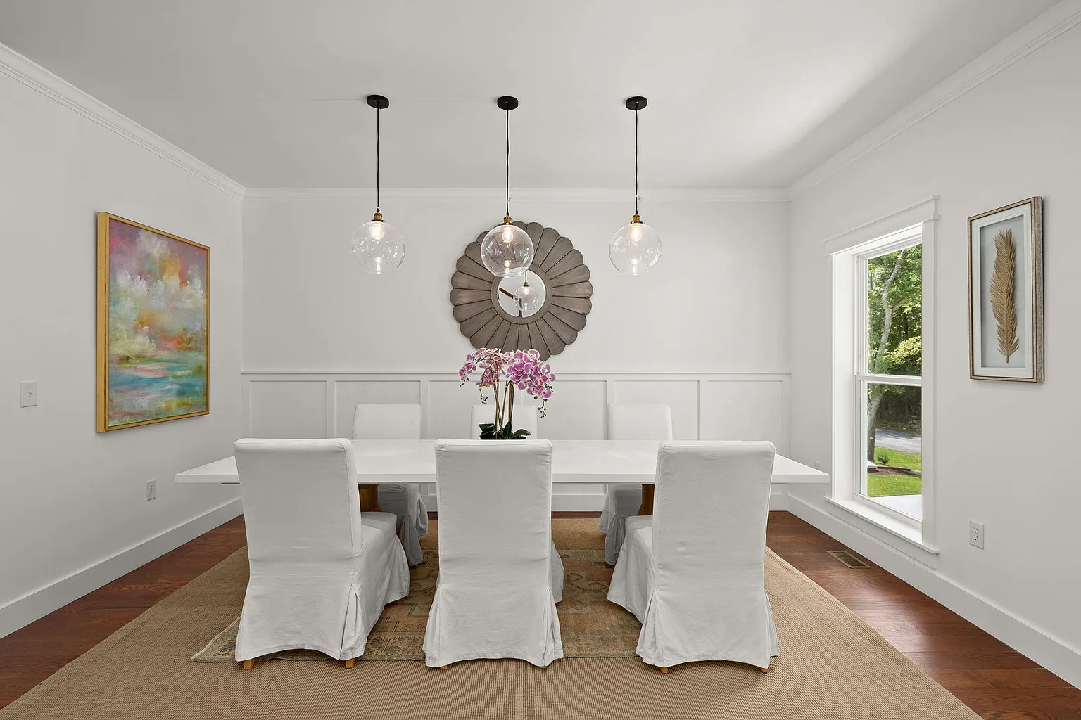 Dining room with white slipcovered chairs and sunburst mirror