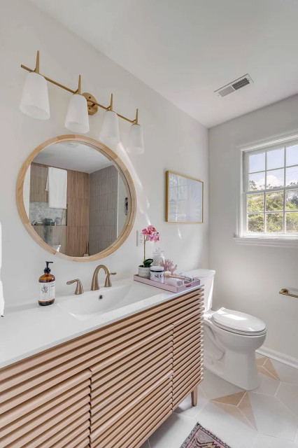 Light-wood vanity with round wood-framed mirror and orchid