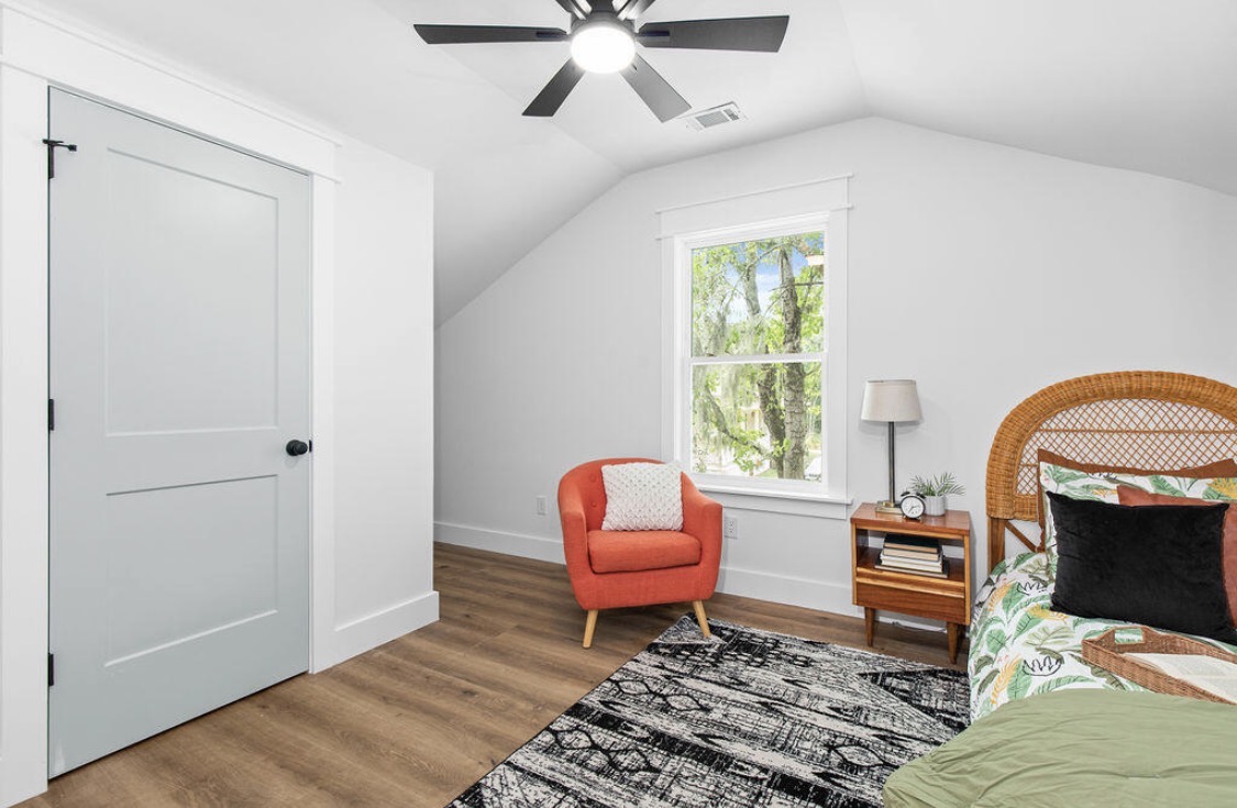 Primary bedroom with rattan headboard and burnt-orange accent chair