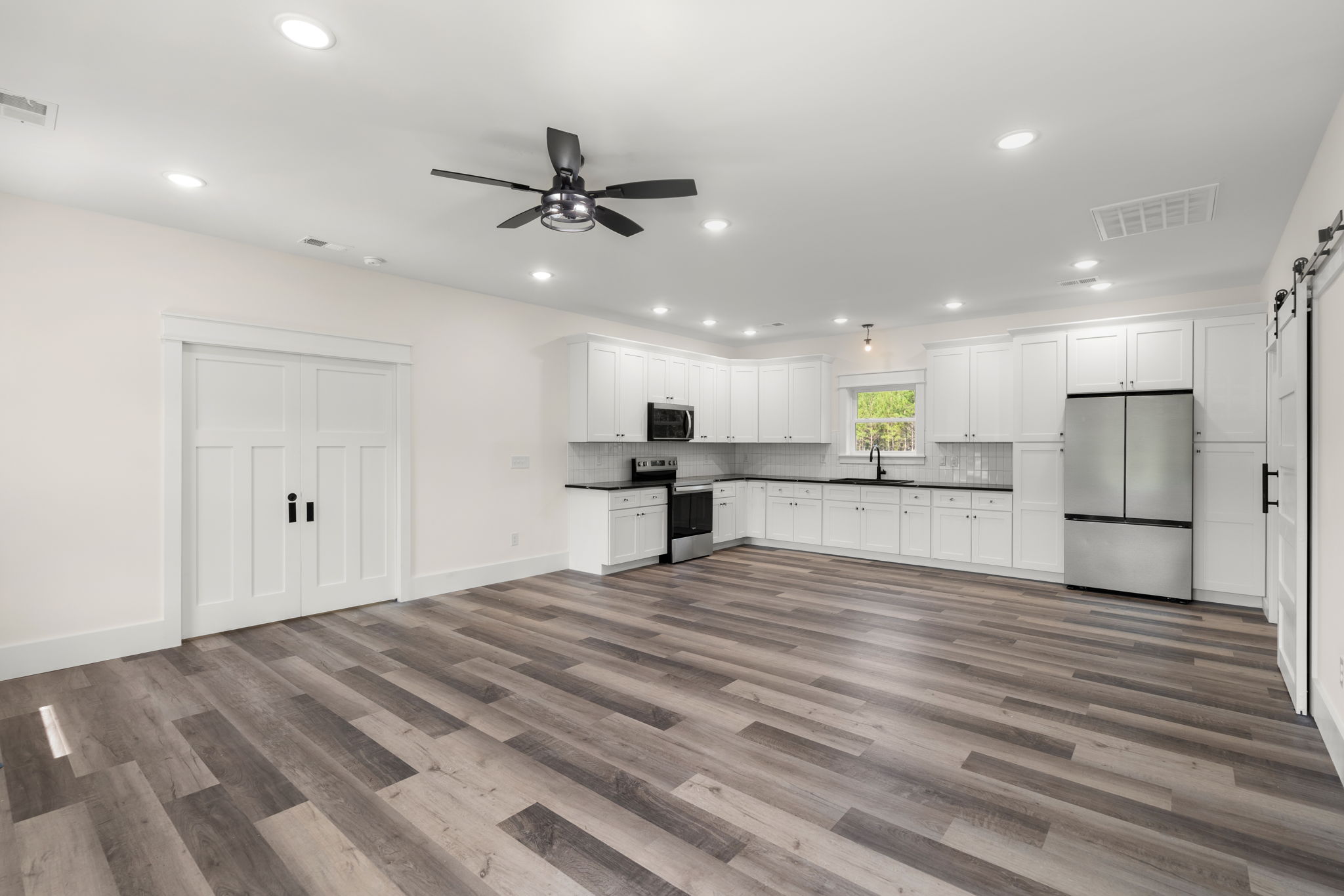 Kitchen and hallway with black quartz counters and double doors